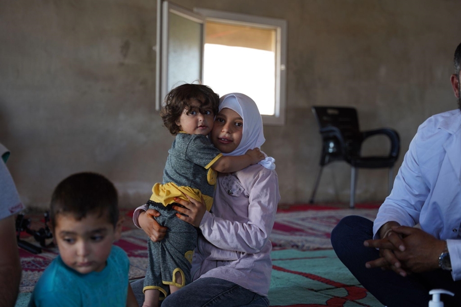  Two of Abu Tarek’s children wait at the vaccination site inside the camp. Photo credit: WHO 