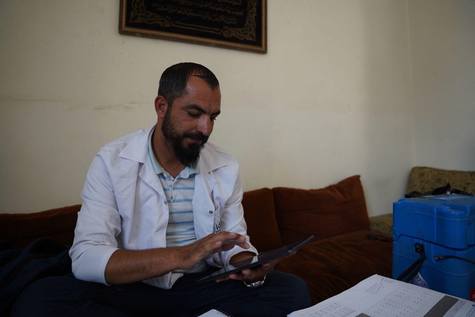  Yasser reviews vaccination records during a routine immunization visit. Photo credit: WHO 