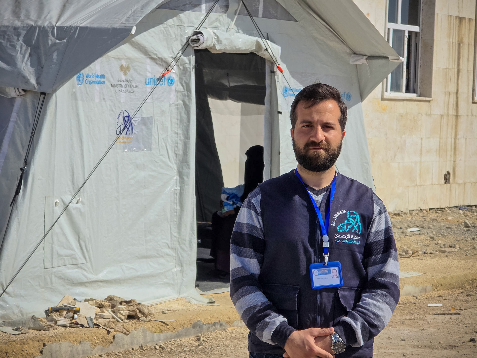Abdallah Lasheen, a health educator with Al Ihsan NGO, stands outside a health tent in northern Aleppo, where he works with families to raise awareness on hygiene, nutrition and disease prevention. Photo credit: WHO