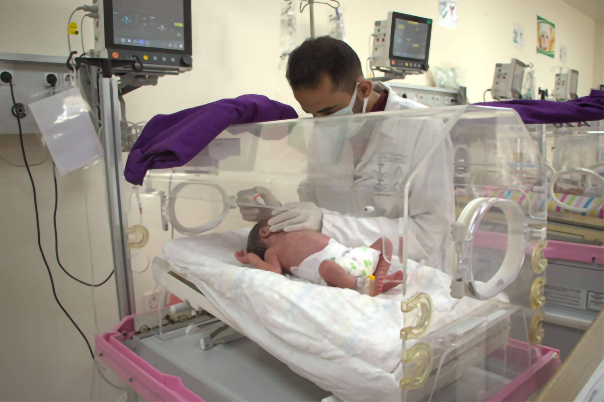 Ahmad Al-Taweel examines infant Mohammad Abbas inside the neonatal unit at Marea National Hospital. Photo credit: WHO