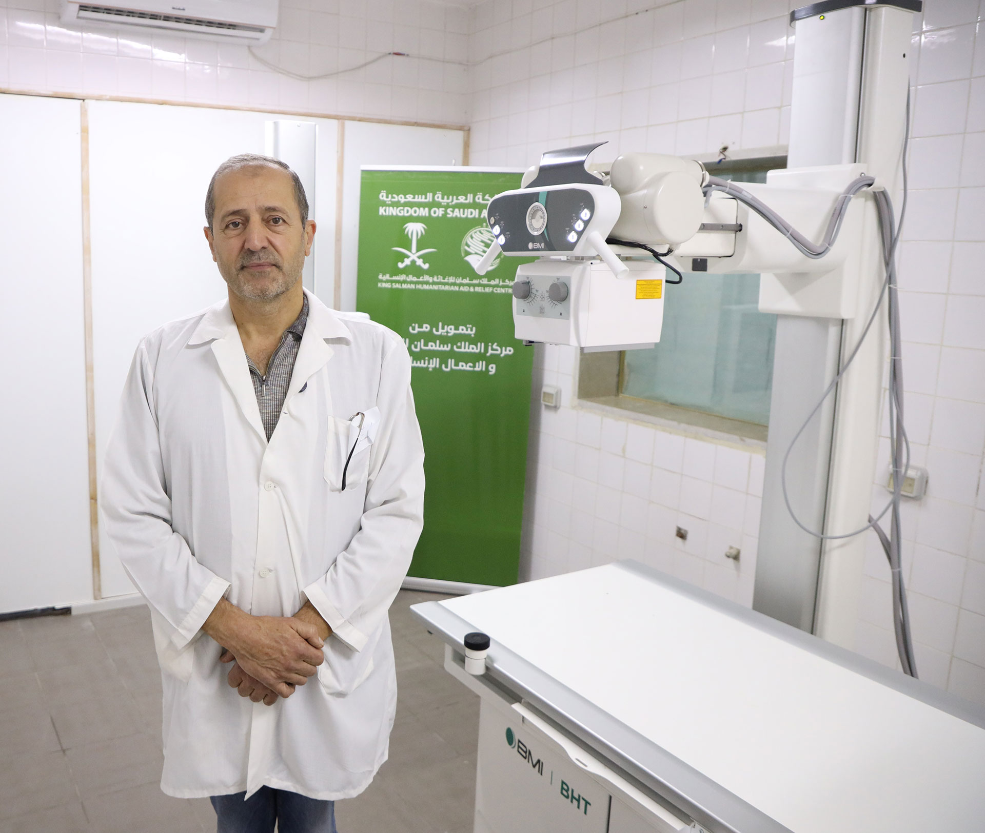 Dr Abdullah Haydar, Head of the Radiology Department at Al-Haffeh Hospital, stands beside the new X-ray machine provided through KSrelief support. Photo credit: WHO