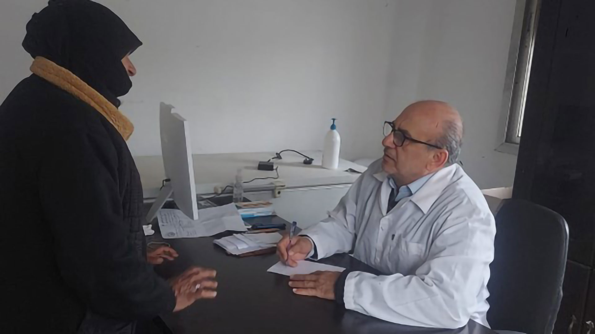 Dr Saad Shoumal, a general practitioner in Hama, consults with a patient at a primary health care centre. Photo credit: WHO