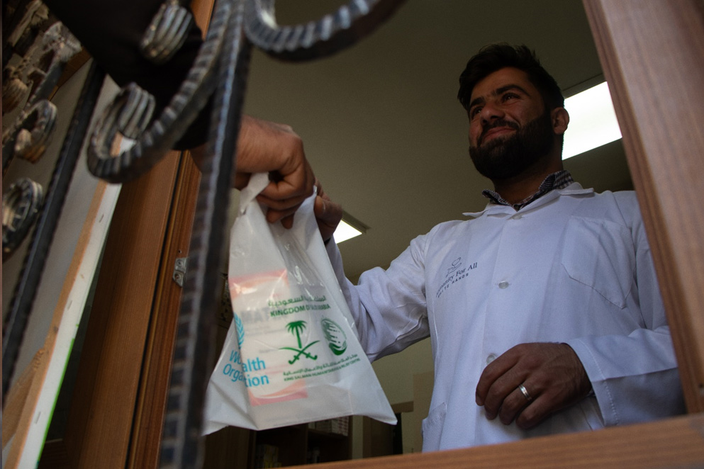 Pharmacist Abdulrahman Kanjo hands prescribed medicines to a patient at Ihtaimalat Health Center in Azaz. Photo credit: WHO