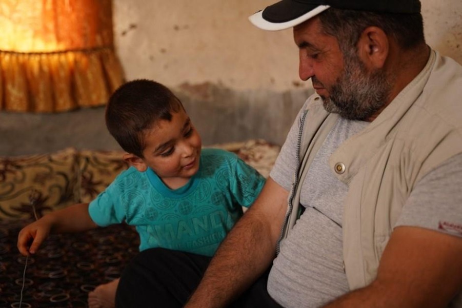 Abu Tarek shares a tender moment with his son inside their shelter after a routine vaccination was administered to his children. Photo credit: WHO